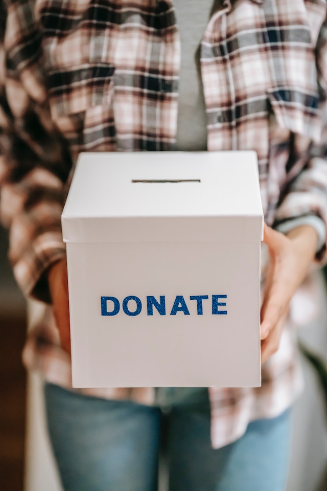 Person holding a box that says donate on it.